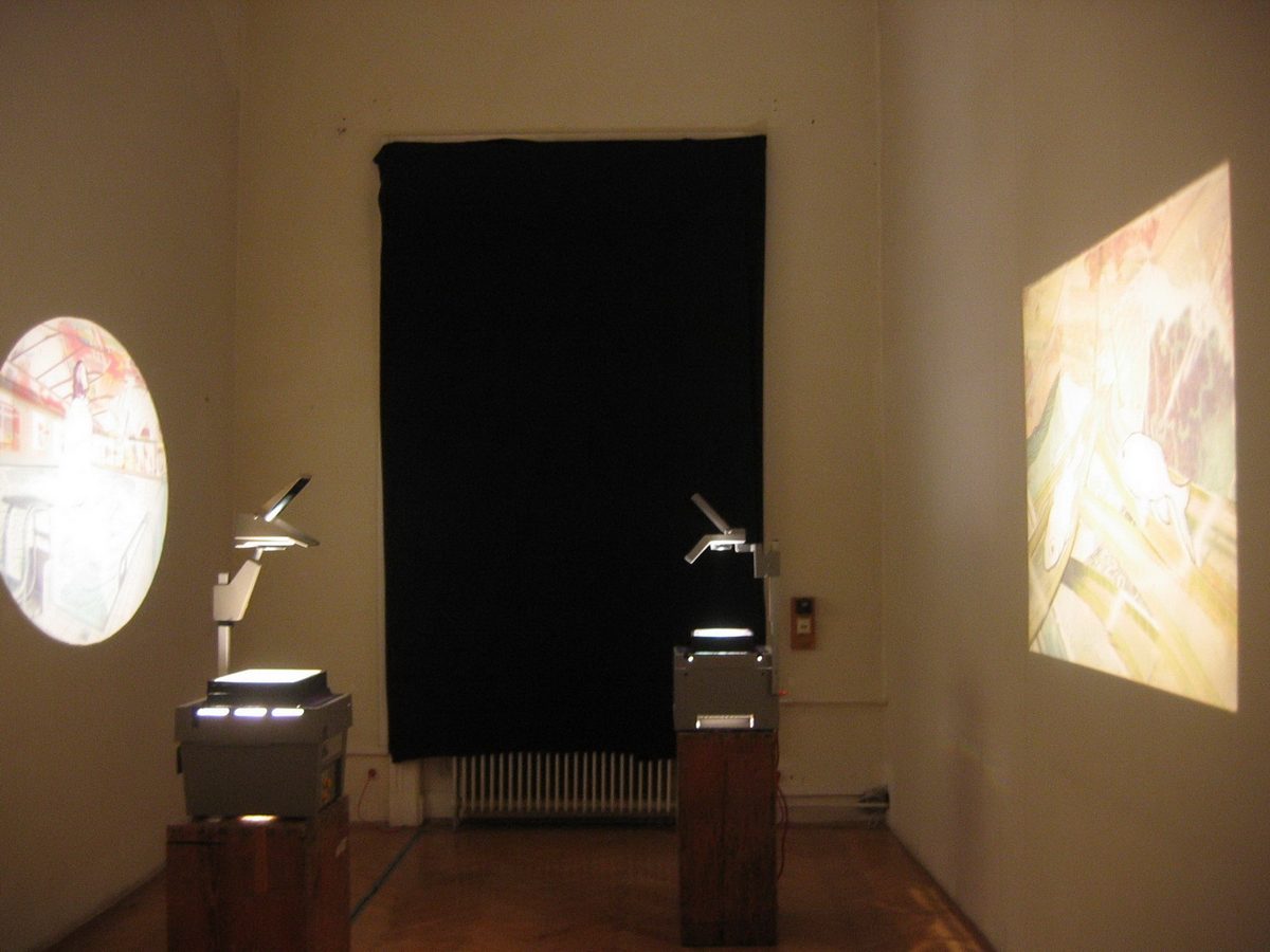 Two overhead projectors on wooden pedestals in the corner of a vaulted brick room, each casting a different hand-drawn image onto opposite walls, with a black cloth hanging on the back wall between them.